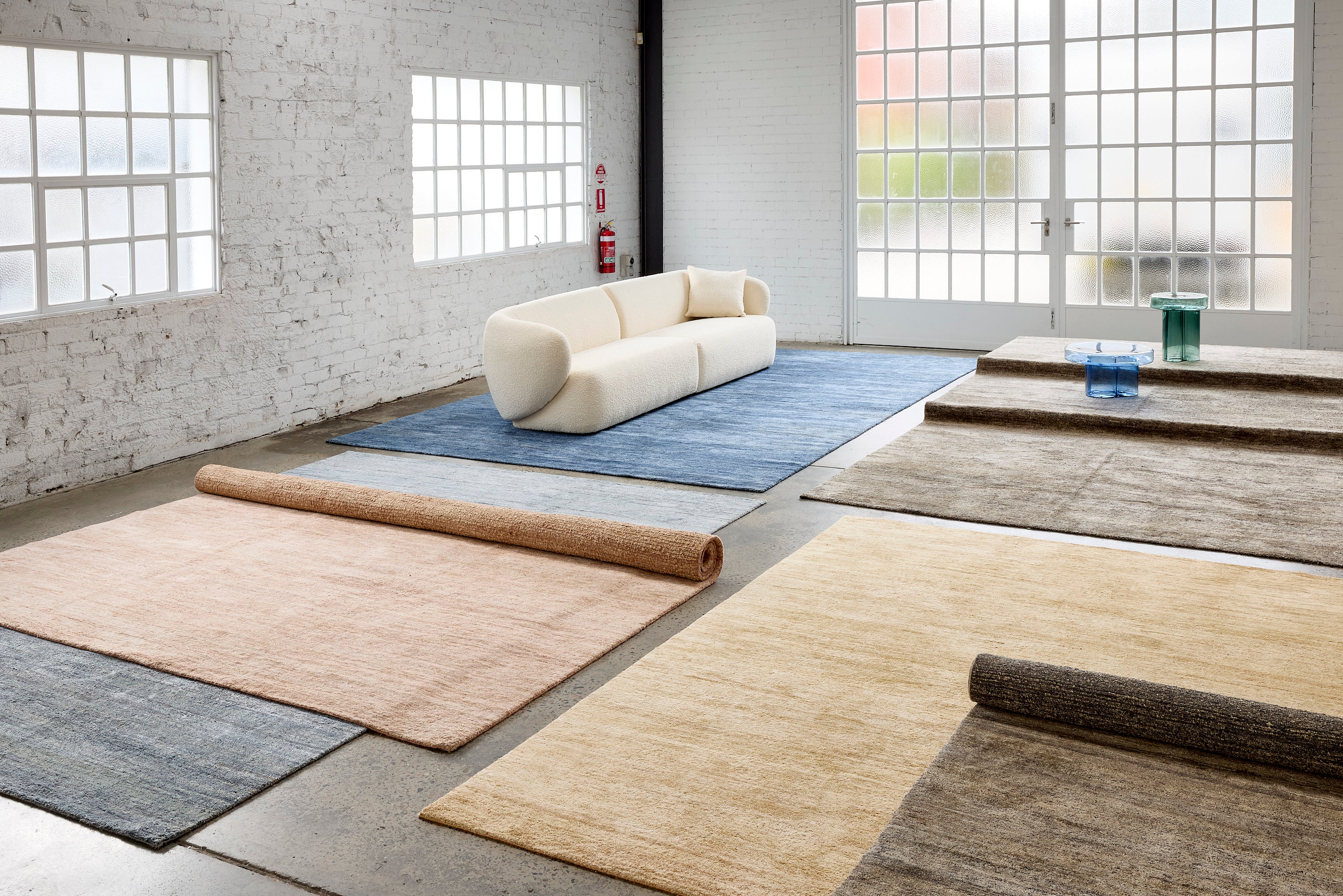 Blue wool and silk rug, grey rug made of wool and silk, Blush rug, gold color rug, Greenish blue color rug, handwoven rugs in a big room with white sofa, glass tea tables and simple interior