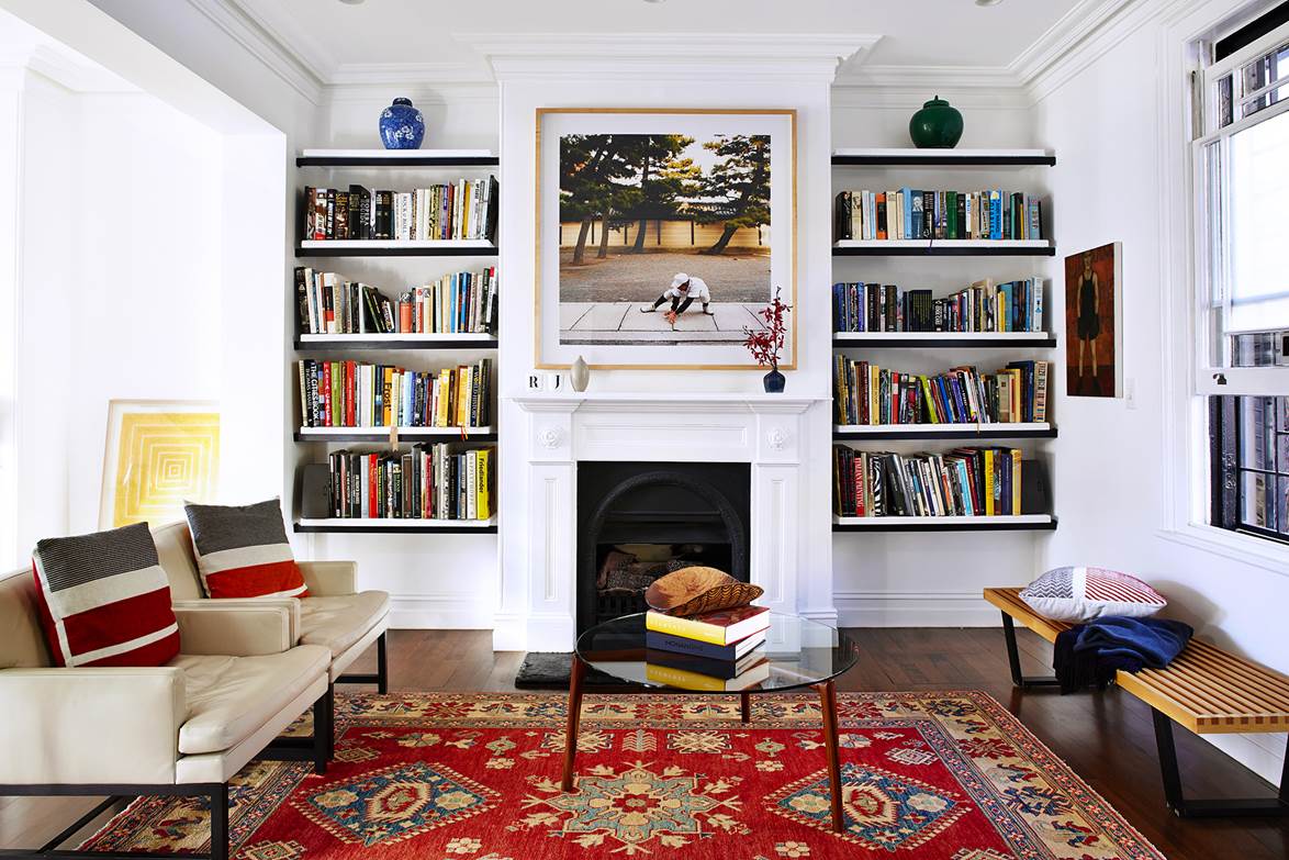 Afghan Caucasian handwoven red rug in study room with sofas, books, paintings, fireplace and beautiful interiors