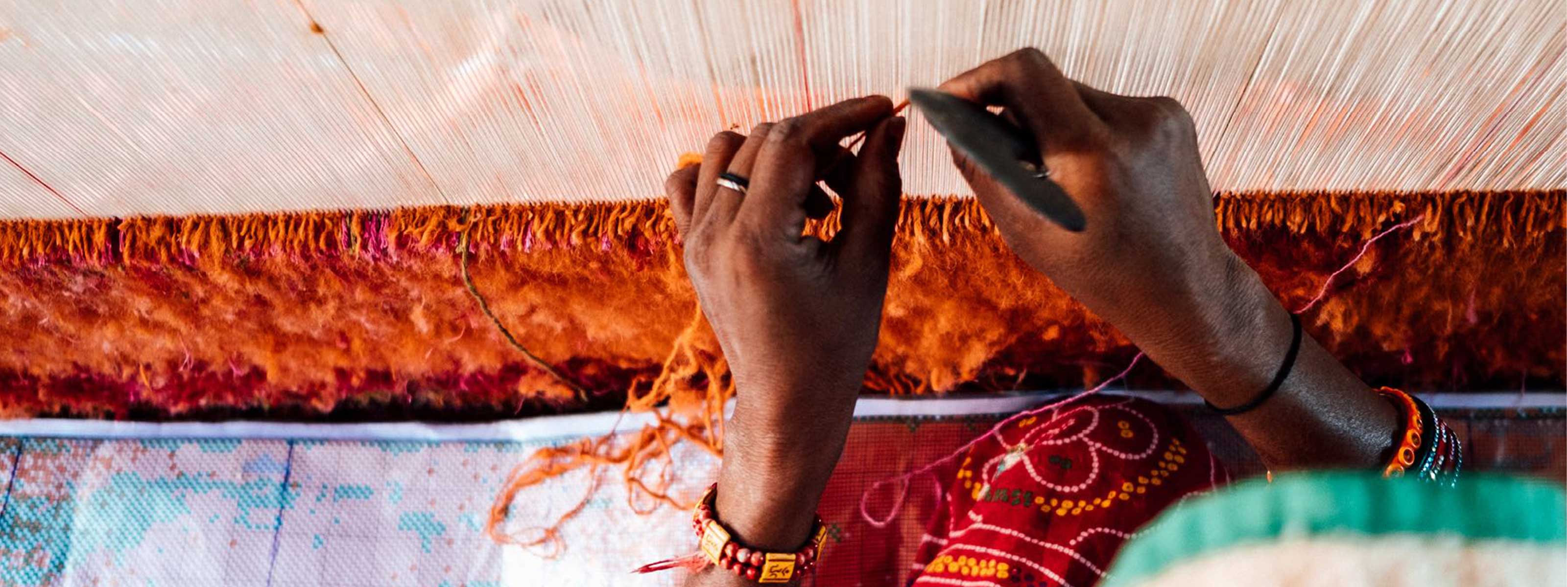 woman weaving rug by hands